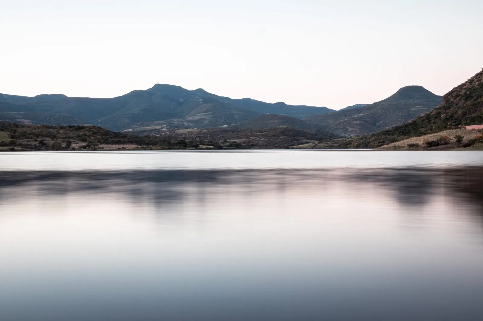 Peaceful lake with a stunning view of distant mountains at dusk.