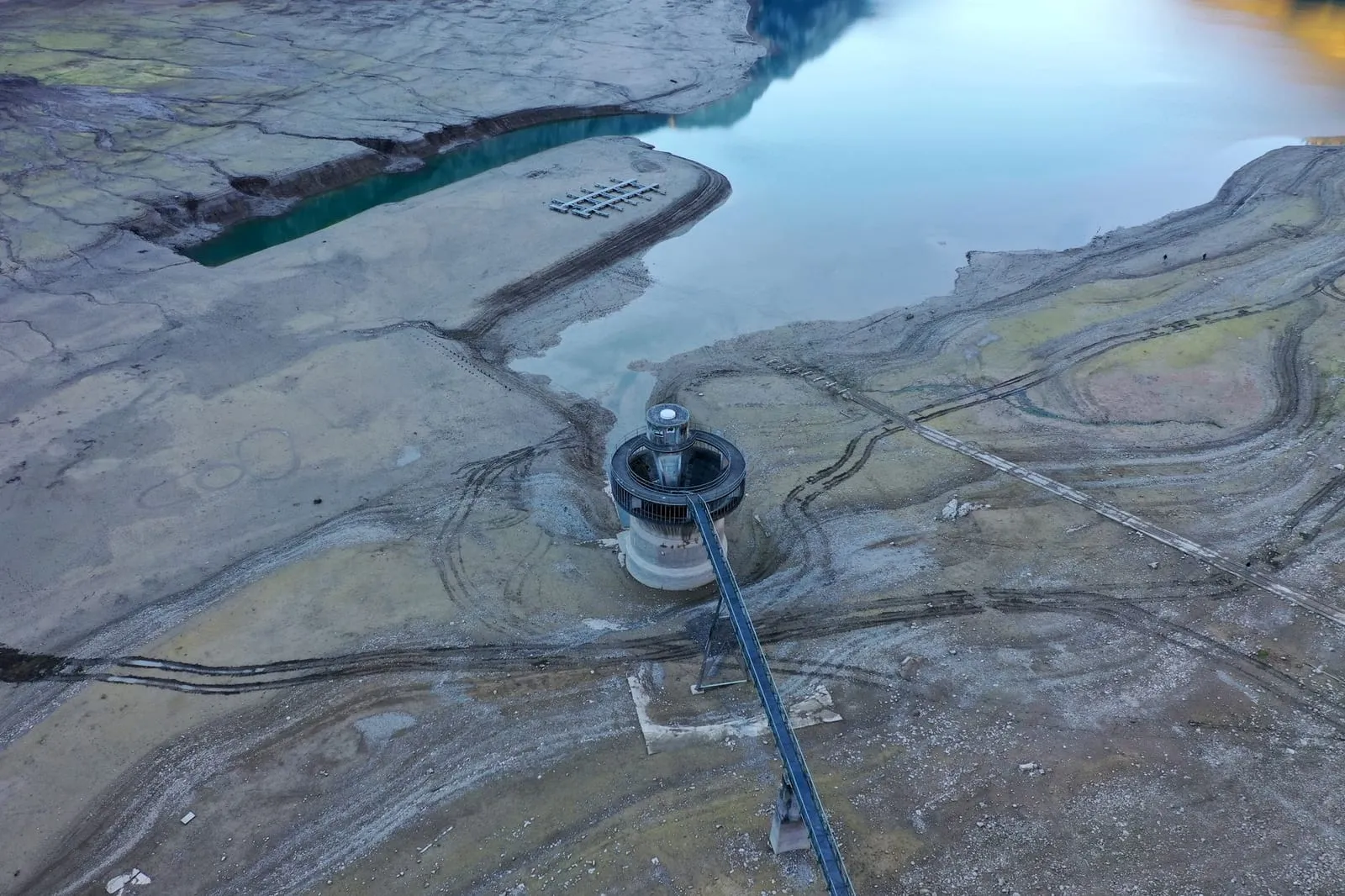 Stunning aerial view of a reservoir structure amidst a dry lake in Glarus, Switzerland.