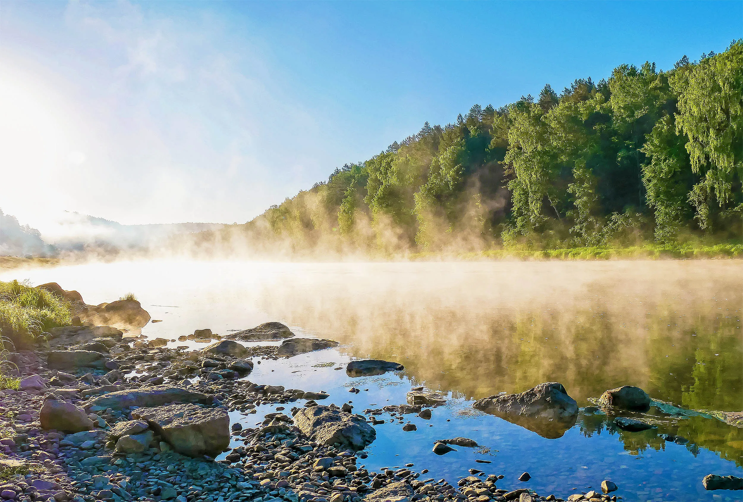 Morning mist rising off a calm river at sunrise as water evaporates into the cooler air