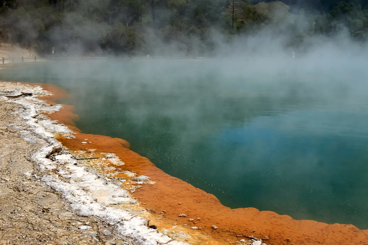 Clouds of water vapour rising from the steaming surface of a hot, mineral-rimmed pool